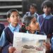 indian students learning in a school with a hindi news paper in hand